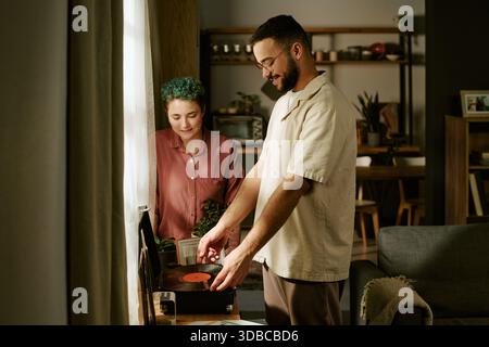 Junge Frau und junger Mann, die drinnen Vinyl-Schallplatten hören Stockfoto