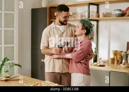 Junge Frau und junger Mann tosten Wein und lächeln zusammen Stockfoto