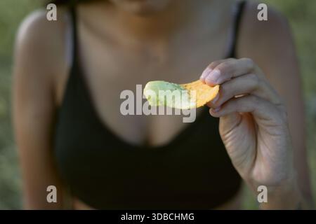 Frau, die einen in cremige Guacamole getauchten Nacho-Chip genießt, feiert den nationalen Nachos-Tag mit einem köstlichen Snack in einer lebendigen Nahaufnahme, die h ausstrahlt Stockfoto