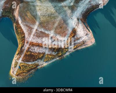 Atemberaubendes Drohnenfoto einer zerklüfteten Halbinsel, umgeben von blauem Wasser, mit unbefestigten Straßen und natürlichen Texturen. Ideal für Reisen, Natur und Landschaft in Südspanien. Stockfoto