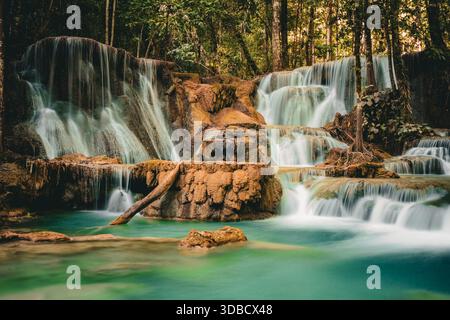 Mehrstöckiger tropischer Wasserfall, der über Felsformationen in klare türkisfarbene Pools fließt, lange ausgesetzte Naturlandschaft umgeben von üppig grünen Wäldern Stockfoto