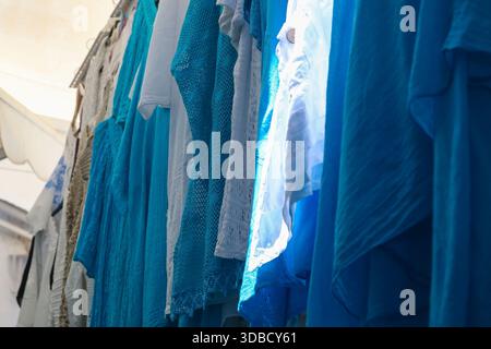 Blaue Textilien hängen vor Geschäften entlang einer Marktstraße in der Altstadt von Rhodos, Griechenland. Stockfoto