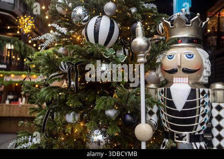 Eine Nahaufnahme einer großen schwarz-weißen Nussknacker-Figur neben einem verzierten weihnachtsbaum mit schwarzen, weißen und silbernen Kugeln und Krieg Stockfoto