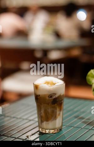 Eiskaffee mit Milchschaum und Espresso-Schichten in klarem Glas auf der Cafétheke, Close Up Coffee Drink Stockfoto