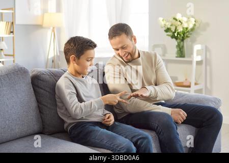 Sohn und liebevoller Vater spielen zusammen im Wohnzimmer, glücklicher Vater und entzückender Junge haben Spaß Stockfoto