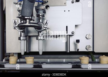 Hersteller für die automatische Herstellung von Eiskegeln. Förderband in Waffelbechern, Creme Brulee. Süßigkeiten, moderne Fabrik. Lebensmittel- und Milchindustrie, Auto Stockfoto