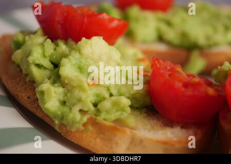 Avocado Toast mit Tomaten serviert auf einem Teller zum Frühstück Stockfoto