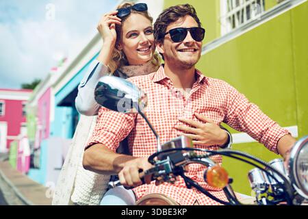 Sonnenbrille, Paar und Reise mit Roller in die Stadt für Urlaubsabenteuer, Sightseeing und Bonding. Umarmen, fröhliche Touristen oder fahren Sie mit dem Motorrad für Stockfoto
