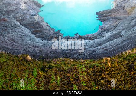 Spektakulärer Vulkan Ijen auf der Insel Java in Indonesien, Blick aus der Vogelperspektive auf einen Vulkankrater und einen blauen vulkanischen See mit dampfenden Lüftungsöffnungen bei Sonnenaufgang Stockfoto