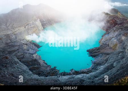 Spektakulärer Vulkan Ijen auf der Insel Java in Indonesien, Blick aus der Vogelperspektive auf einen Vulkankrater und einen blauen vulkanischen See mit dampfenden Lüftungsöffnungen bei Sonnenaufgang Stockfoto