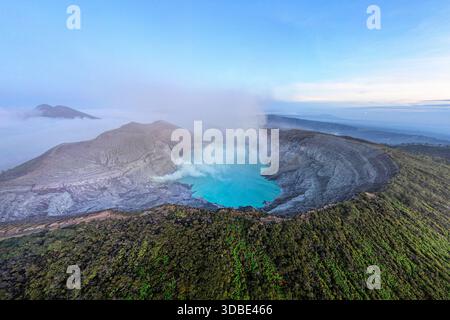 Spektakulärer Vulkan Ijen auf der Insel Java in Indonesien, Blick aus der Vogelperspektive auf einen Vulkankrater und einen blauen vulkanischen See mit dampfenden Lüftungsöffnungen bei Sonnenaufgang Stockfoto