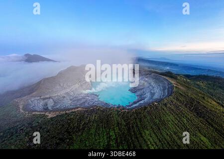 Spektakulärer Vulkan Ijen auf der Insel Java in Indonesien, Blick aus der Vogelperspektive auf einen Vulkankrater und einen blauen vulkanischen See mit dampfenden Lüftungsöffnungen bei Sonnenaufgang Stockfoto