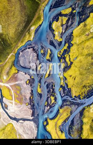 Aus der Vogelperspektive ziehen sich Gletscherflüsse durch die Landschaft und schaffen einen atemberaubenden Kontrast zwischen dem türkisfarbenen Wasser und dem goldgrünen moosigen Terrai Stockfoto