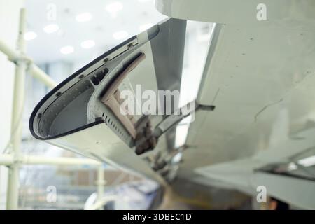 Nahaufnahme eines Flugzeugflügelklappenmechanismus in einer Instandhaltungseinrichtung. Werkzeuge und Ausrüstung sind sichtbar, was die komplizierte Konstruktion unterstreicht Stockfoto
