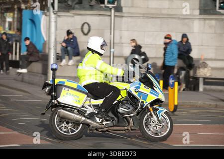 Dublin, Irland - 10. Dezember 2025 - Ein Garda auf dem Motorrad, von der Roads Police Unit, reagiert auf einen Notfall mit blauen Lichtern auf der O'Connell Street in Dublin, die Straßenszenen in der irischen Hauptstadt darstellen Stockfoto