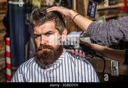 Mann, der Friseur im Friseur besucht. Friseurfrau schneidet einen bärtigen Mann in einem Friseurladen Stockfoto