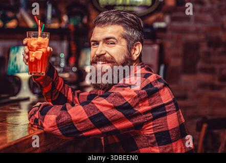 Porträtmann, der Orangensaft trinkt. Tropischer alkoholischer, frischer Cocktail. Bartmanncocktail Stockfoto