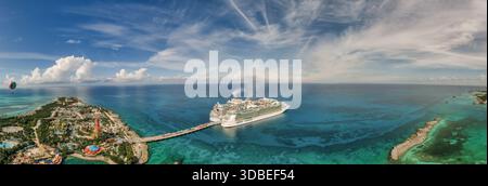 Aus der Vogelperspektive auf das türkisfarbene Wasser, das die Kreuzfahrtschiffe umgibt, die am lebhaften Pier nahe dem Inselresort Nassau, Bahamas angedockt sind. Stockfoto
