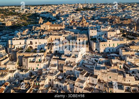 Aus der Vogelperspektive auf sonnengeküsste weiße Gebäude, die den Hügel hinunter fallen, ein Labyrinth aus Dächern und verwinkelten Gassen, die zu den historischen Kirchen, Ostuni, Stockfoto