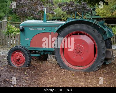 Grüner Hanomag-Traktor Mit Großen Roten Rädern Auf Unbefestigtem Boden. Stockfoto