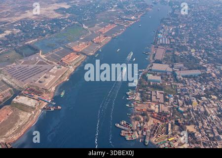 Aus der Vogelperspektive auf den Buriganga River, der durch eine Landschaft aus Ziegelöfen, Industriegebäuden und Booten fließt, zeigt den Kontrast zwischen Natur und Stockfoto
