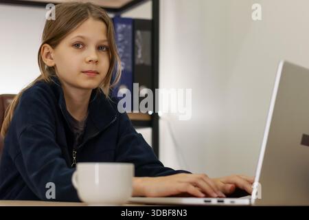 Eine junge Studentin, die auf einem Laptop in hellem Innenraum schreibt Stockfoto