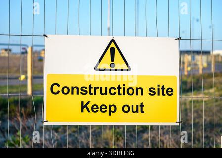 Halten Sie das Schild auf einem Metallzaun auf einer Baustelle bei Sonnenuntergang fern Stockfoto