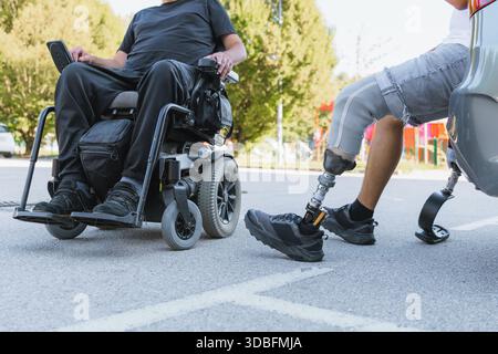 Zwei behinderte Freunde verbringen Zeit im Freien, einer in einem Rollstuhl und der andere mit einer Beinprothese. Stockfoto