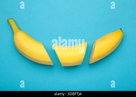 Schneiden Sie Bananen, Scheiben auf pastellblauem Hintergrund. Minimalistisches Konzept. Draufsicht Stockfoto