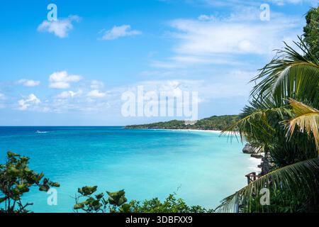 Klares türkisfarbenes Wasser trifft auf weißen Sand und üppiges Grün am Bira Beach in Sulawesi, Indonesien, unter einem hellen tropischen Himmel Stockfoto