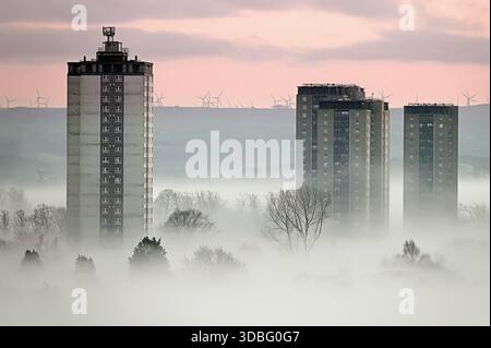 Glasgow, Schottland, Großbritannien. Dezember 2025. Wetter in Großbritannien: Niedriger Nebel, der auf einen plötzlichen Temperaturabfall über dem westlichen Ende der Stadt hinweist, sah die Türme von Scotstoun bei Sonnenuntergang ihre Anwesenheit durch den absteigenden Nebel bekannt machen. Credit Gerard Ferry/Alamy Live News Stockfoto