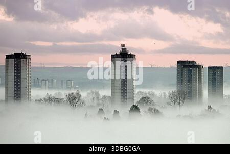 Glasgow, Schottland, Großbritannien. Dezember 2025. Wetter in Großbritannien: Niedriger Nebel, der auf einen plötzlichen Temperaturabfall über dem westlichen Ende der Stadt hinweist, sah die Türme von Scotstoun bei Sonnenuntergang ihre Anwesenheit durch den absteigenden Nebel bekannt machen. Credit Gerard Ferry/Alamy Live News Stockfoto
