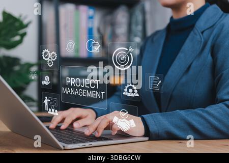 Projektmanagement-Software-Konzept. Geschäftsfrau, die an einem Laptop arbeitet, mit einem Symbol, das Planung, Projektmanager, Aufgabenverfolgung, Ressourcenzuweisung, Stockfoto