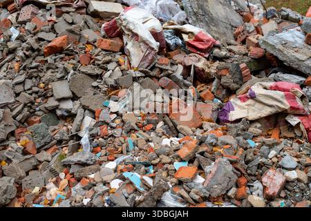 Haufen von Bauschutt. Zerquetschte, gerissene Bauabfälle in Form von Ziegeln, Schlackenblockfragmenten und Betonschutt nach einem Gebäude Stockfoto