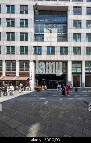 MAILAND, ITALIEN, 06.19.2025: Ein modernes Stadtgebäude mit McDonald's Eingang, Cafés im Freien und Fußgängern, die auf einem plaza spazieren. Helles Tageslicht Stockfoto