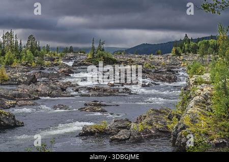 Der Nordic River in Lappland stürzt über verwitterte Felsen und kreiert eine wilde, abgelegene Landschaft unter einem wilden Himmel, frisches, kräftiges Wasser in einem unberührten NO Stockfoto