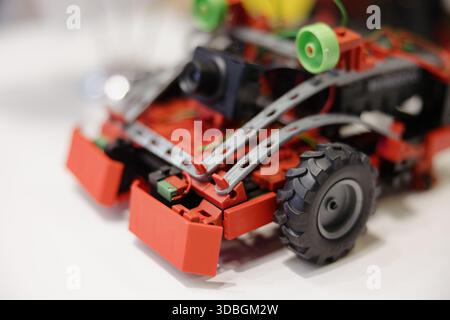 Kreatives rotes Roboterfahrzeug zeigt in einer Technikwerkstatt am Tag die technischen Fähigkeiten Stockfoto