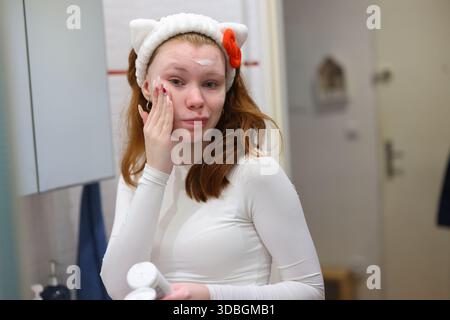 Nahaufnahme Porträt der Frau mit Gesichtscreme im Badezimmer perfekt für Hautpflege Bildung Schönheit Tutorials und Gesundheit Marketing Stockfoto