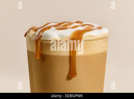 Großaufnahme von Caramel Latte Kaffeeglas auf beigem Hintergrund Stockfoto