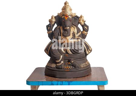 Eine Ganesha-Statue mit goldenen Verzierungen auf einem Holzsockel. Ideal für Hausaltar, Meditationsräume oder reflektierende kulturelle Einrichtung Stockfoto