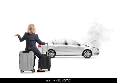 Rückansicht einer verwirrten Frau, die auf einem Koffer sitzt und ein kaputtes Fahrzeug auf weißem Hintergrund betrachtet Stockfoto