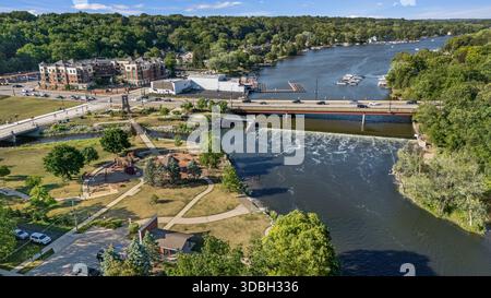 Blick aus der Vogelperspektive auf die Innenstadt von Algonquin Illinois entlang des Fox River mit Straßenlandschaften am Flussufer, Brückenüberquerung, Yachthafen und lokalen Unternehmen. Stockfoto