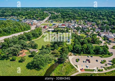 Blick aus der Vogelperspektive auf die Innenstadt von Algonquin Illinois entlang des Fox River mit Straßenlandschaften am Flussufer, Brückenüberquerung, Yachthafen und lokalen Unternehmen. Stockfoto