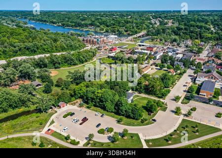 Blick aus der Vogelperspektive auf die Innenstadt von Algonquin Illinois entlang des Fox River mit Straßenlandschaften am Flussufer, Brückenüberquerung, Yachthafen und lokalen Unternehmen. Stockfoto