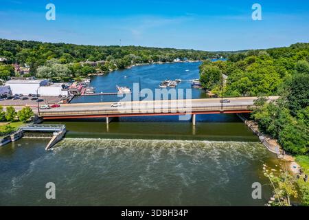 Blick aus der Vogelperspektive auf die Innenstadt von Algonquin Illinois entlang des Fox River mit Straßenlandschaften am Flussufer, Brückenüberquerung, Yachthafen und lokalen Unternehmen. Stockfoto