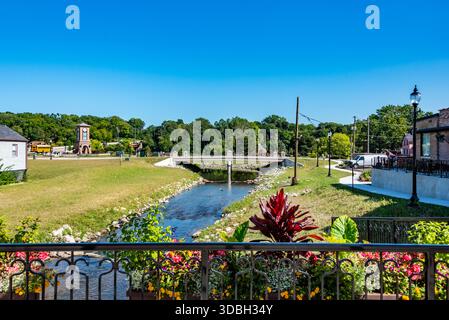 Blick aus der Vogelperspektive auf die Innenstadt von Algonquin Illinois entlang des Fox River mit Straßenlandschaften am Flussufer, Brückenüberquerung, Yachthafen und lokalen Unternehmen. Stockfoto
