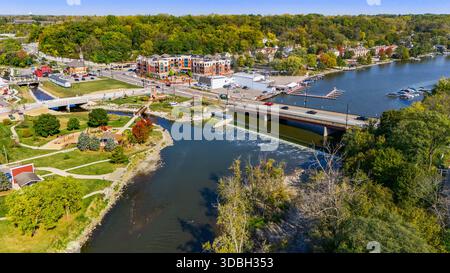 Blick aus der Vogelperspektive auf die Innenstadt von Algonquin Illinois entlang des Fox River mit Straßenlandschaften am Flussufer, Brückenüberquerung, Yachthafen und lokalen Unternehmen. Stockfoto