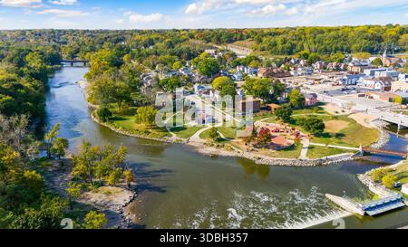 Blick aus der Vogelperspektive auf die Innenstadt von Algonquin Illinois entlang des Fox River mit Straßenlandschaften am Flussufer, Brückenüberquerung, Yachthafen und lokalen Unternehmen. Stockfoto