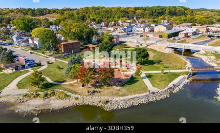 Blick aus der Vogelperspektive auf die Innenstadt von Algonquin Illinois entlang des Fox River mit Straßenlandschaften am Flussufer, Brückenüberquerung, Yachthafen und lokalen Unternehmen. Stockfoto