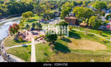 Blick aus der Vogelperspektive auf die Innenstadt von Algonquin Illinois entlang des Fox River mit Straßenlandschaften am Flussufer, Brückenüberquerung, Yachthafen und lokalen Unternehmen. Stockfoto